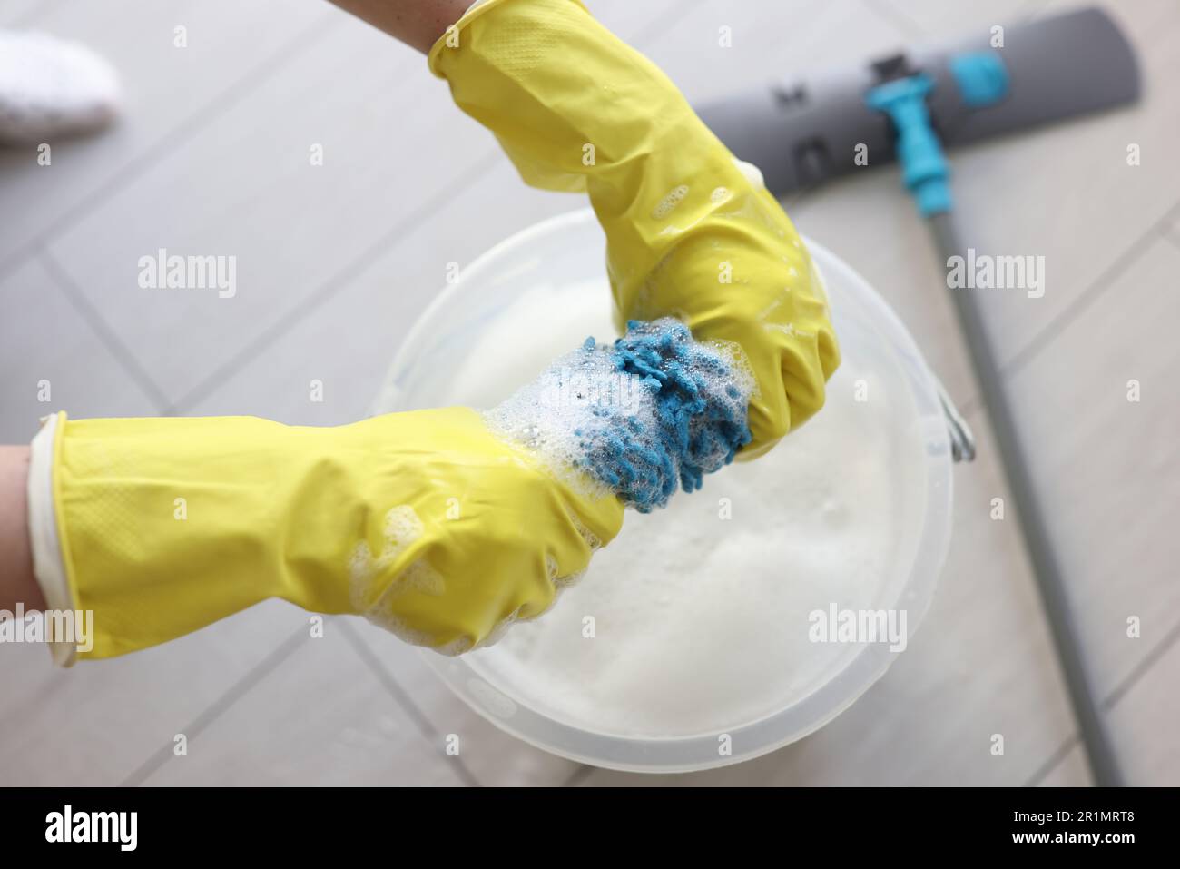 Janitor in rubber gloves wrings mop rag over bucket Stock Photo - Alamy