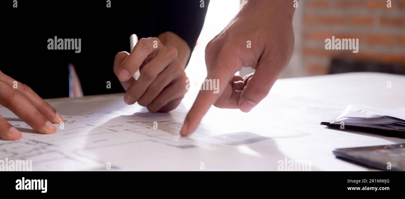 Closeup hands young caucasian architect woman looking laptop and working drawing blueprint for planning building house, engineer thinking and sketchin Stock Photo