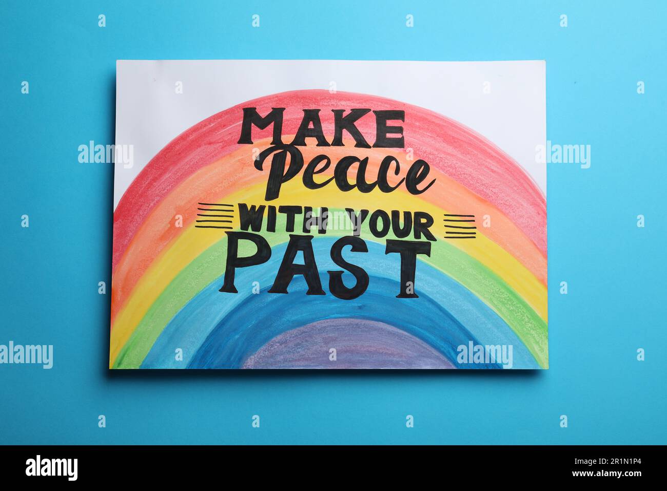 Painting with rainbow and life-affirming phrase Make Peace With Your Past on light blue background Stock Photo