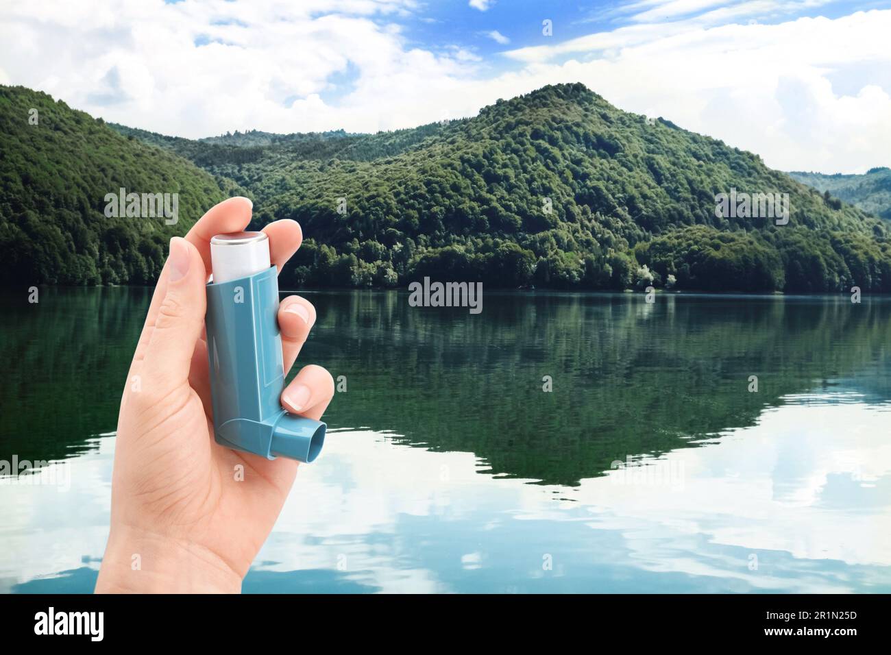 Woman with asthma inhaler near lake, closeup. Emergency first aid during outdoor recreation Stock Photo