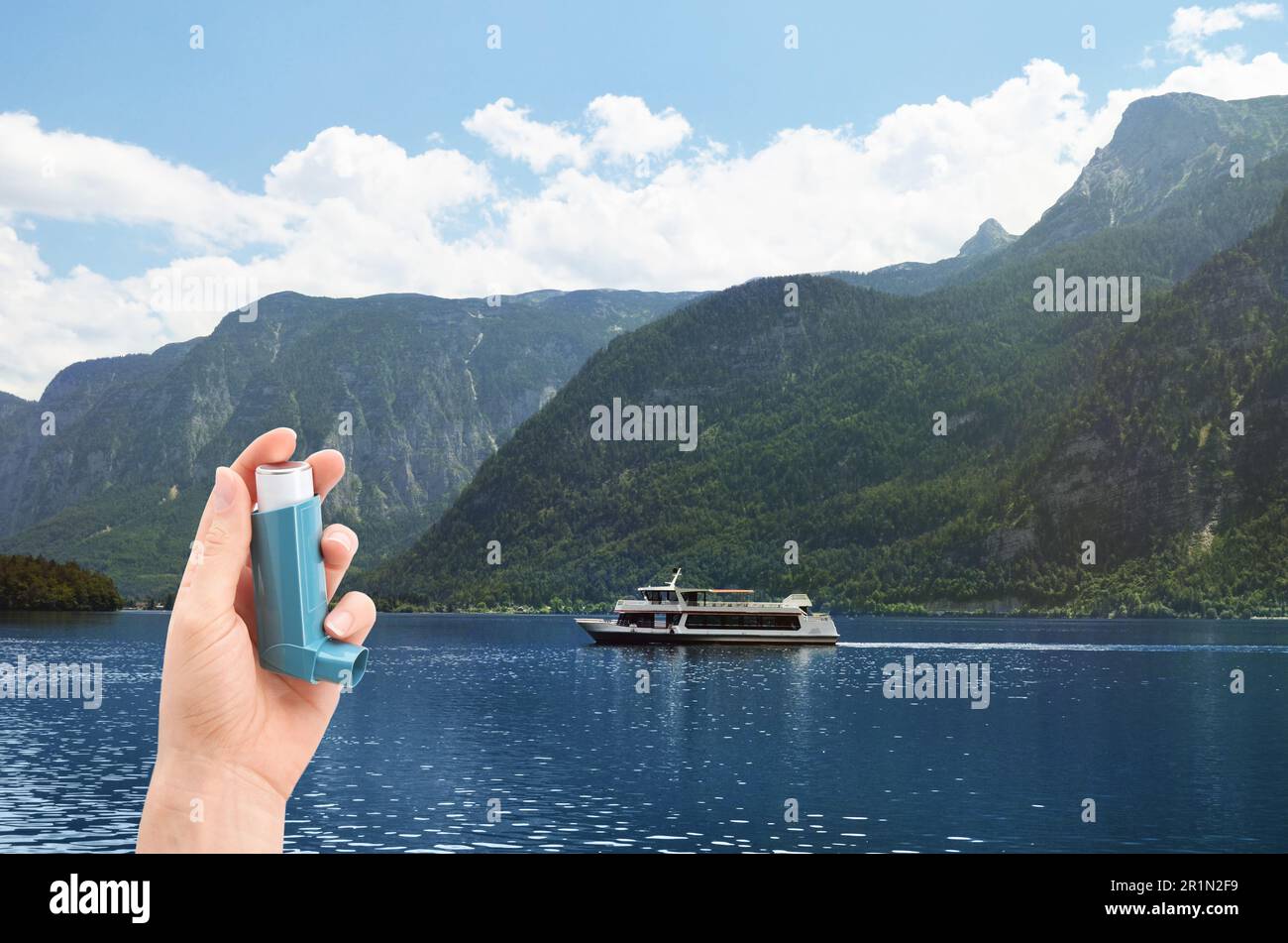 Woman with asthma inhaler near lake, closeup. Emergency first aid during outdoor recreation Stock Photo