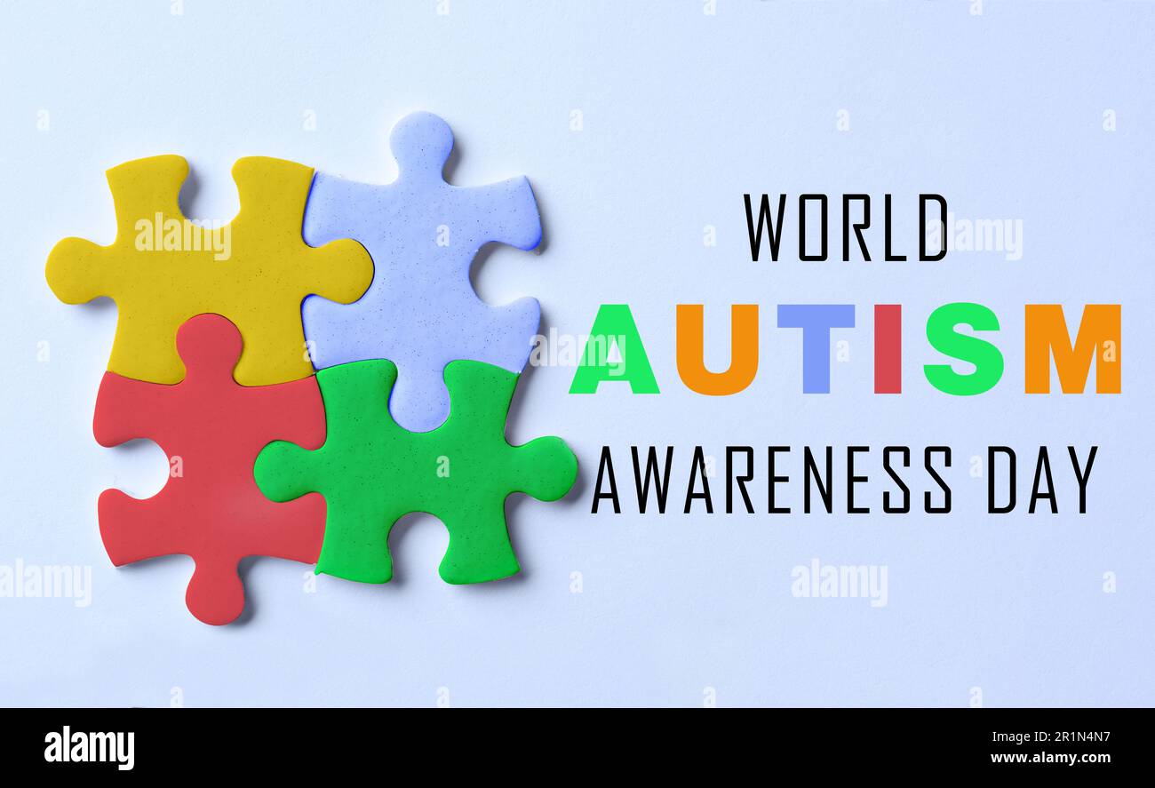 World Autism Awareness Day. Colorful puzzle pieces and text on light blue background, top view Stock Photo