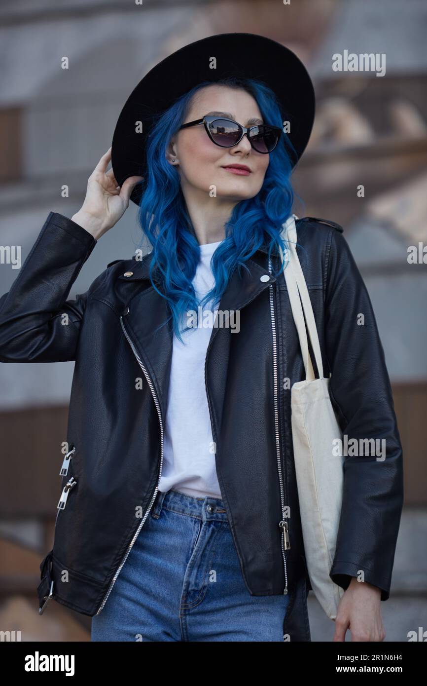 Beautiful diverse woman with blue hair. Young adult female wearing stylish hipster hat black leather jacket and cotton tote bag in the city street Stock Photo Alamy