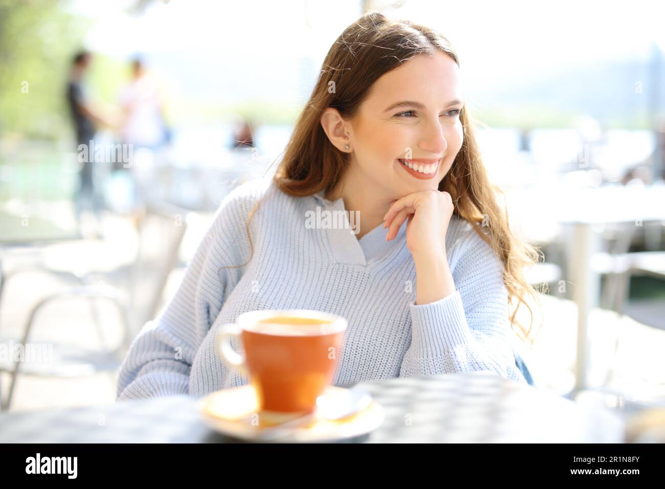 Happy woman looks away sitting in a coffee shop terrace Stock Photo