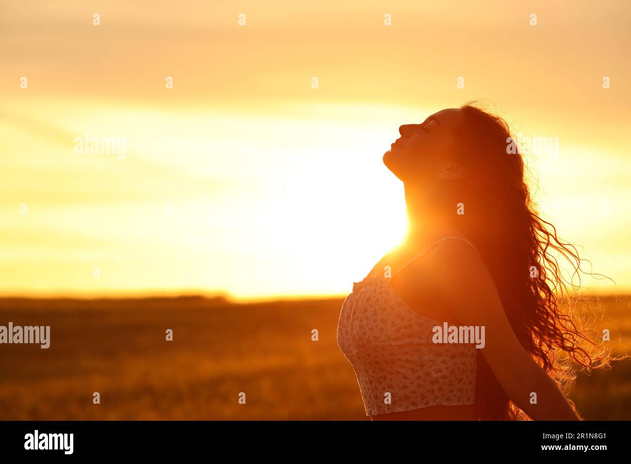 Profile of a female silhouette breathing fresh air at sunset in a field Stock Photo