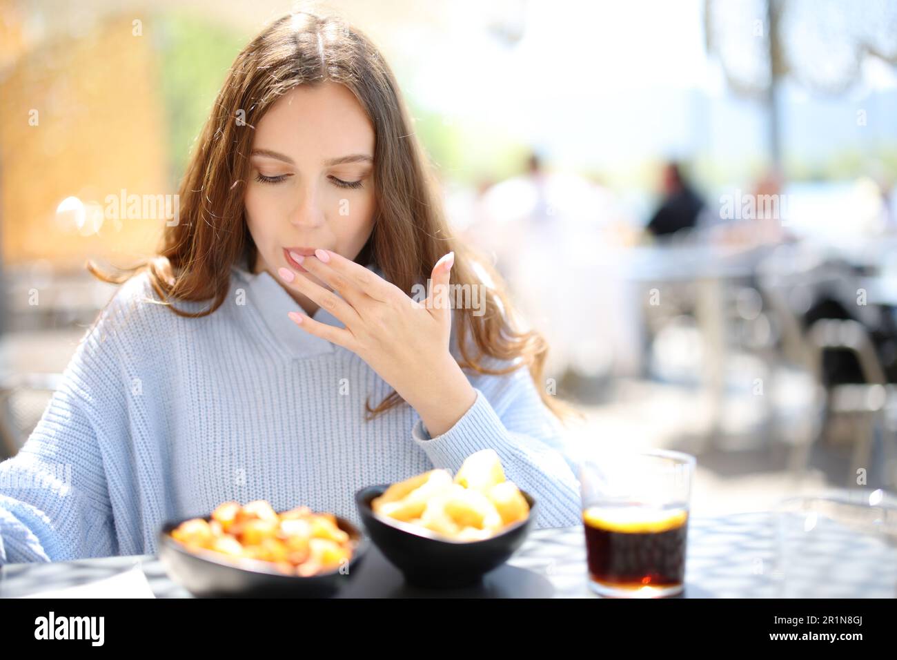Restaurant customer eating and licking finger in a terrace Stock Photo