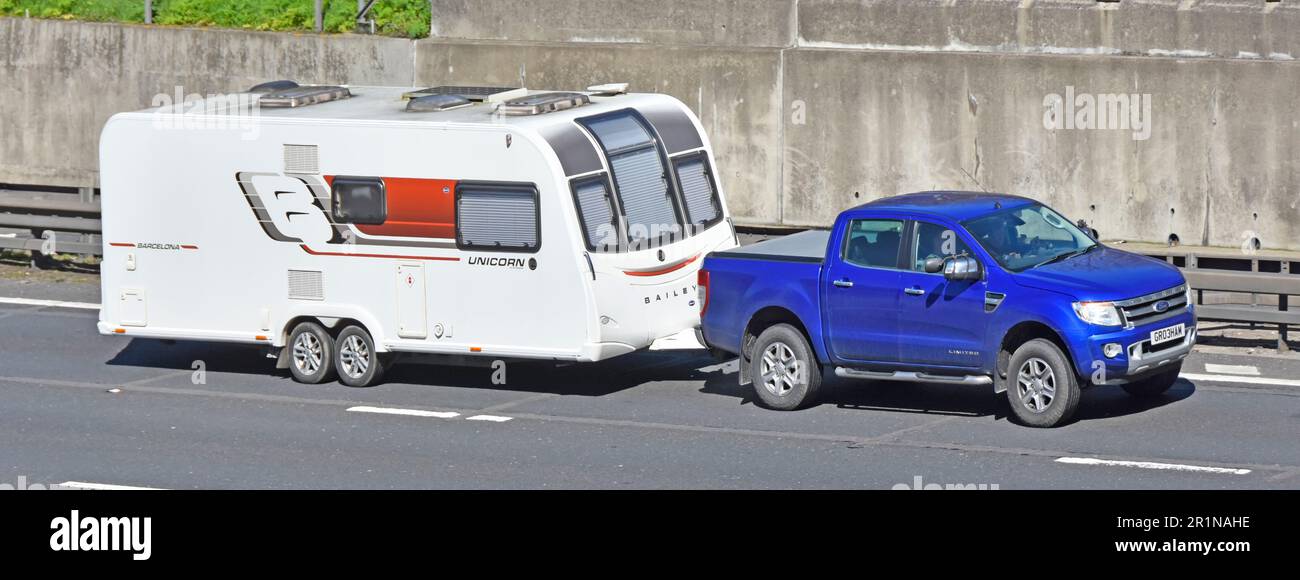 Blue Ford Limited pick up van driver towing Bailey Unicorn Barcelona twin axle holiday caravan side front and roof views driving M25 motorway Essex UK Stock Photo