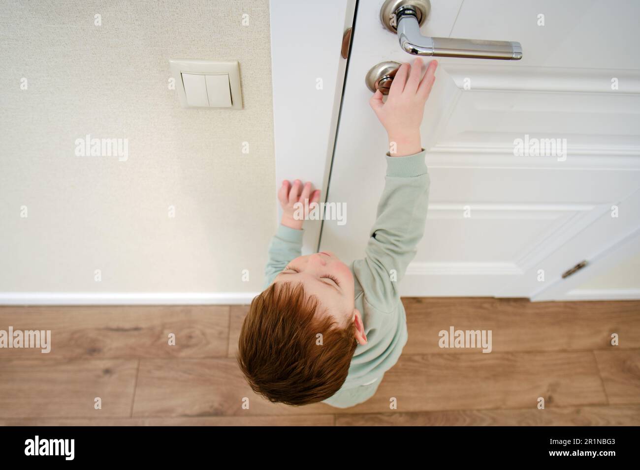 Little baby opens the door lock. Small child touches the closed lock on the  white door. Kid aged one year nine months Stock Photo - Alamy