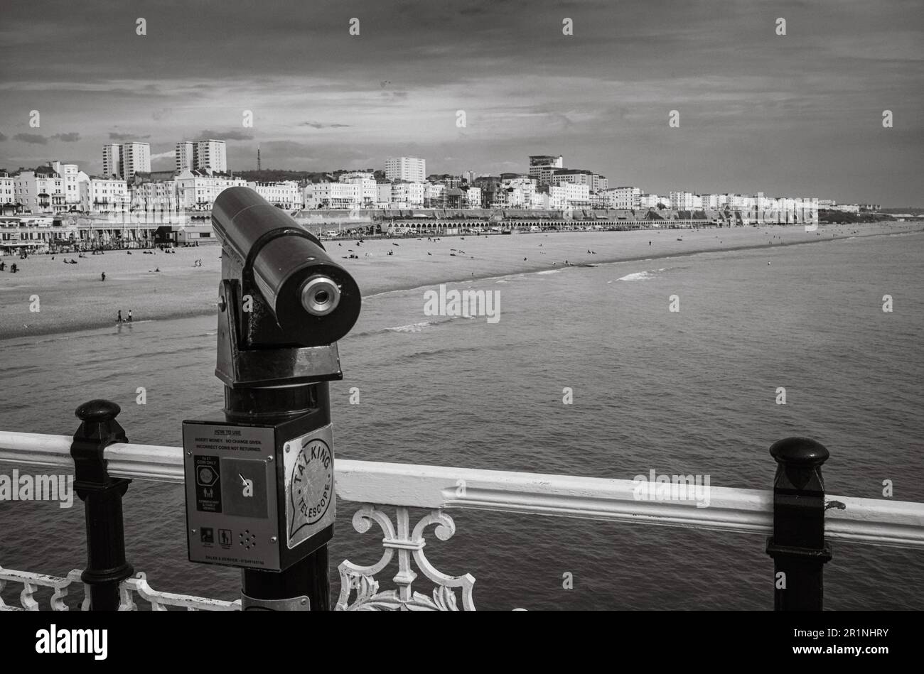 A coin operated talking telescope on Brighton Pier points towards the beach and  seafront at Brighton, East Sussex, UK. The pier dates back to 1899 an Stock Photo