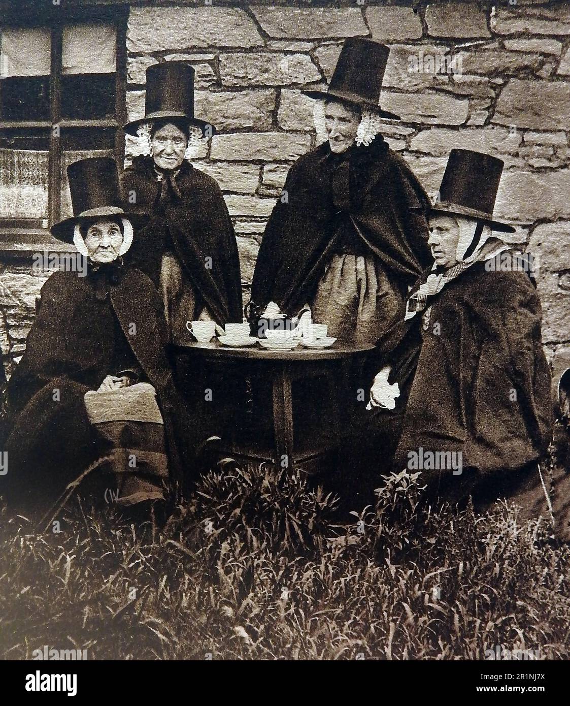An old image of four Welsh women in the national dress of Wales, having afternoon tea in 1939. Stock Photo
