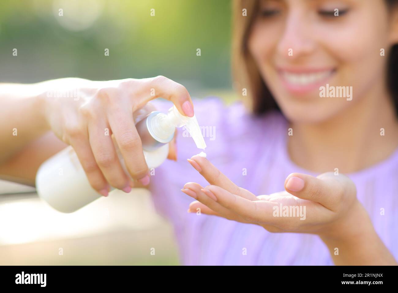 Close up portrait of a happy woman applying hydration cream on finger outdoor Stock Photo