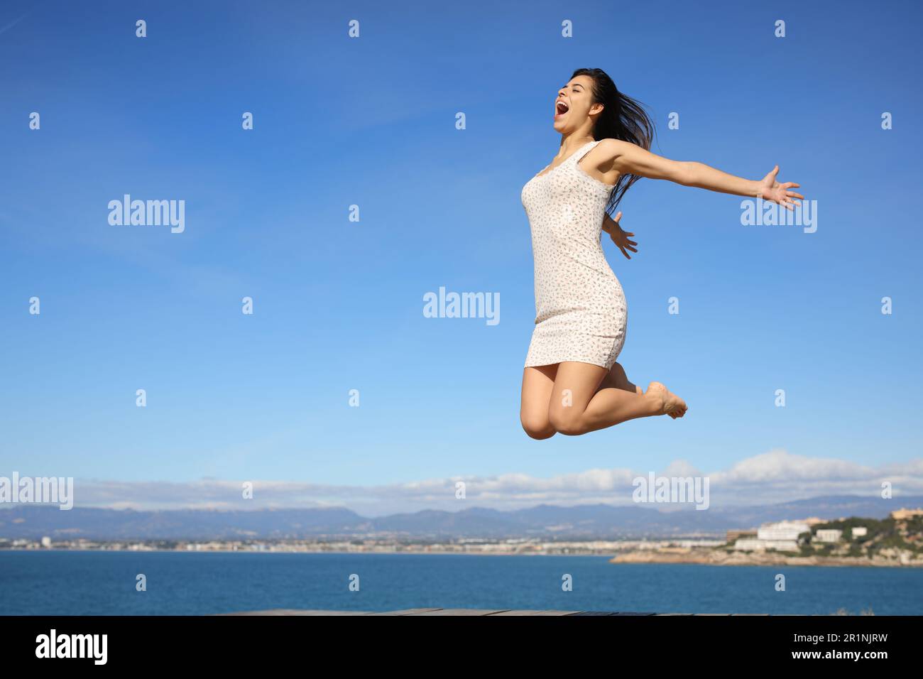 Happy woman jumping in the coast celebrating summer vacation Stock Photo