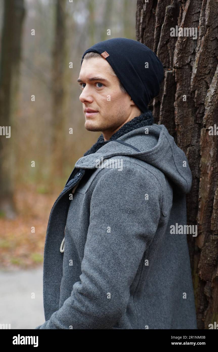 young man leaning against a tree in winter Stock Photo