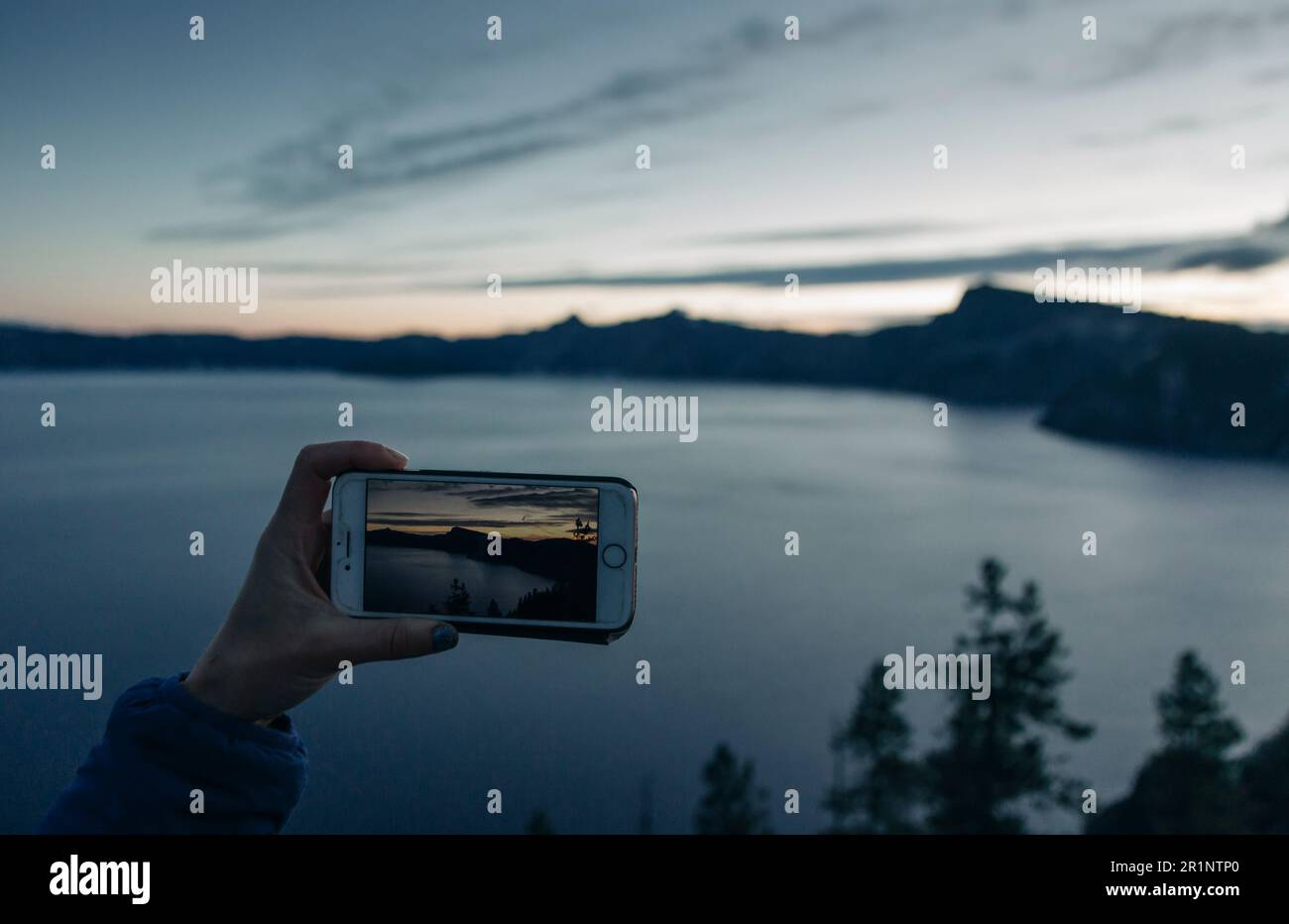 A woman takes a photo of Crater Lake National Park in Oregon. Stock Photo