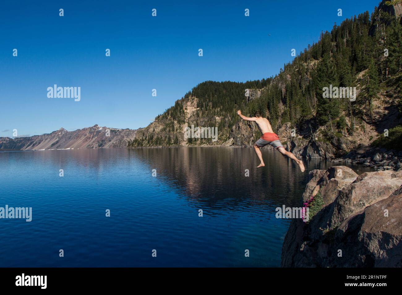 A young man jumps into the cold, clear waters of Crater Lake. Stock Photo