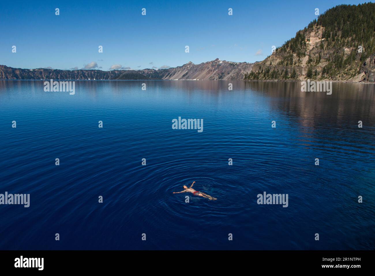 A young man swims in the cold, clear waters of Crater Lake. Stock Photo