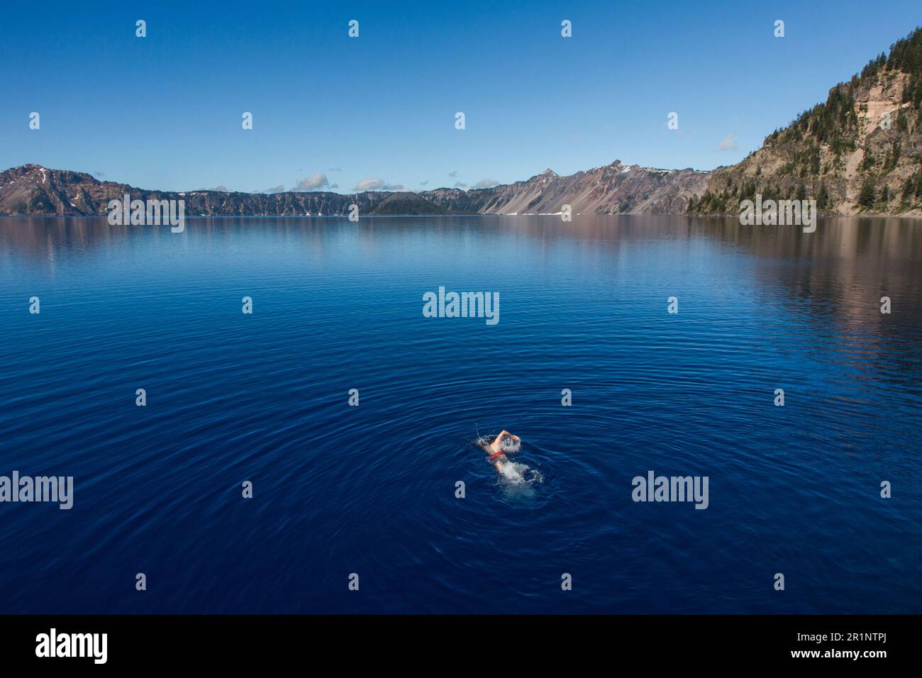 A young man swims in the cold, clear waters of Crater Lake. Stock Photo