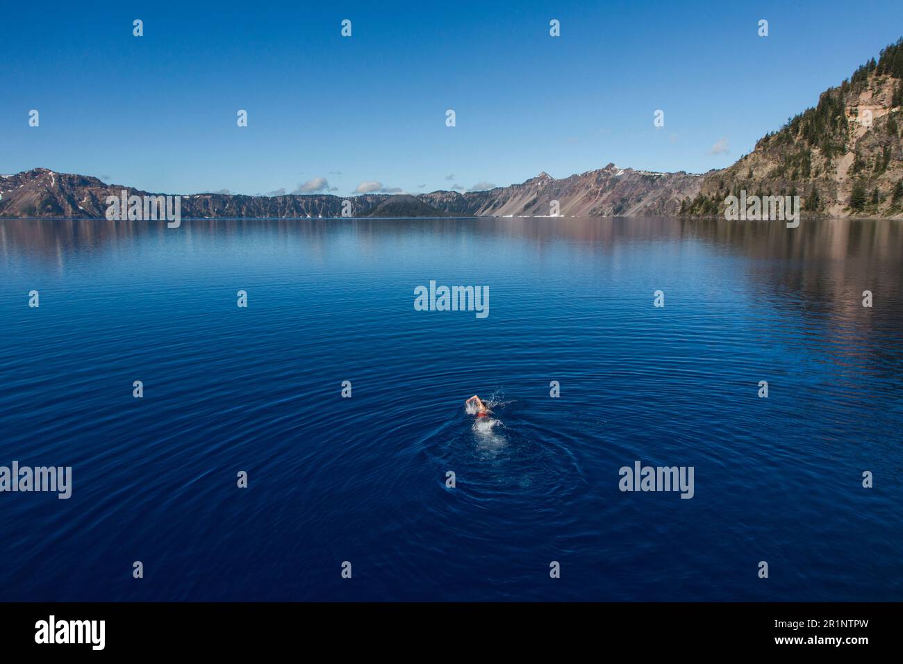 A young man swims in the cold, clear waters of Crater Lake. Stock Photo
