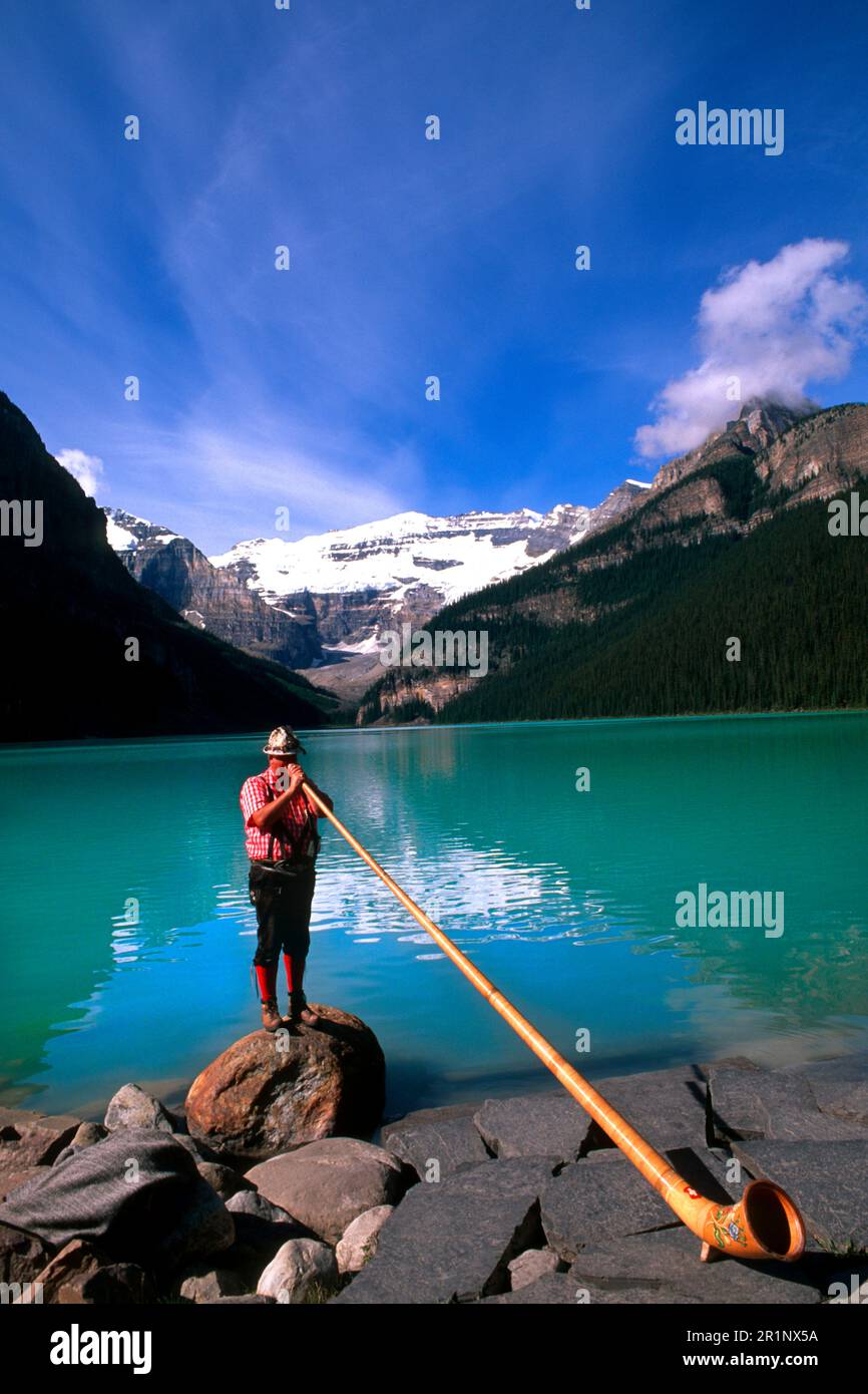Swiss Alphorn player at Lake Louise in Banff Canada Stock Photo