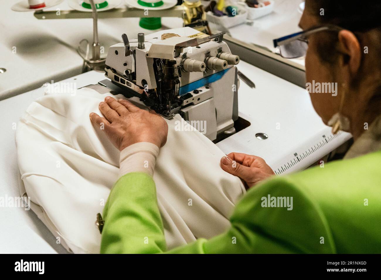 dressmaker woman sews with machine in her sewing workshop Stock Photo