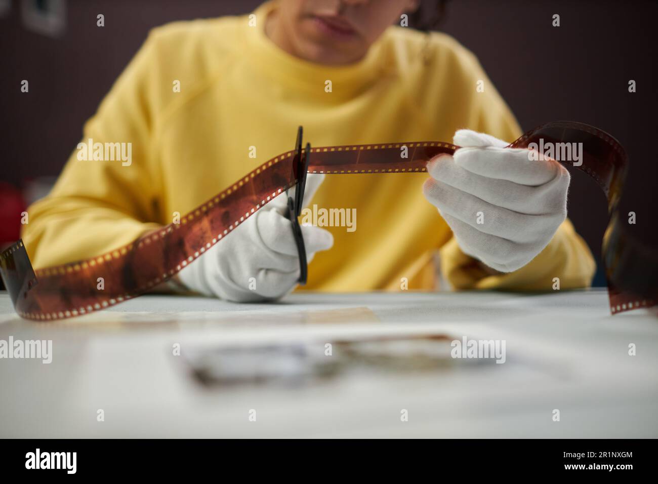 Closeup of photographer in white gloves cutting photo film with
