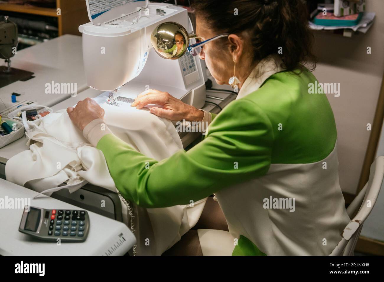 dressmaker woman sews with machine in her sewing workshop Stock Photo