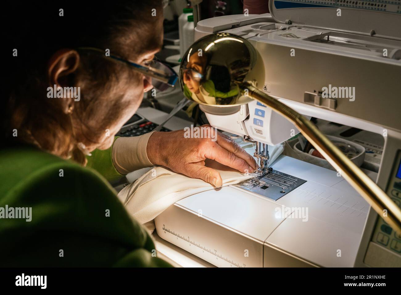 dressmaker woman sews with machine in her sewing workshop Stock Photo