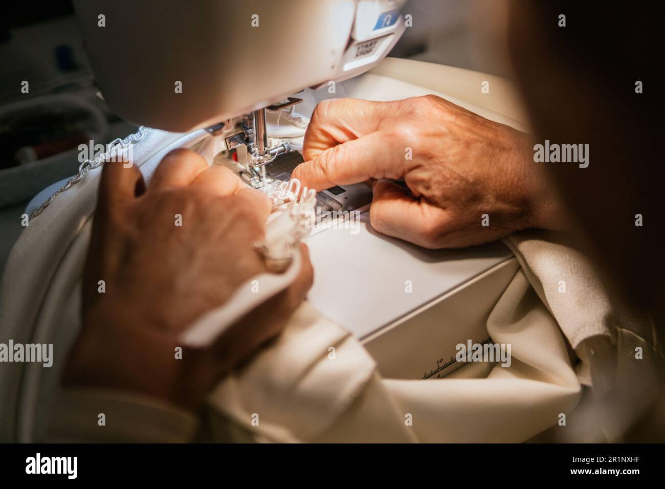 hands of dressmaker woman sews with machine in her sewing workshop Stock Photo
