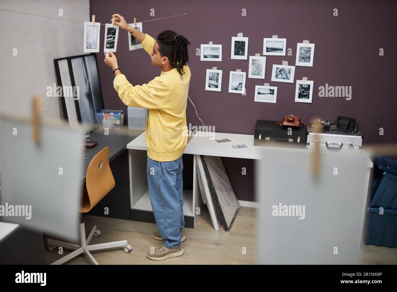 Photographer hanging printed black and white photos while working with ...