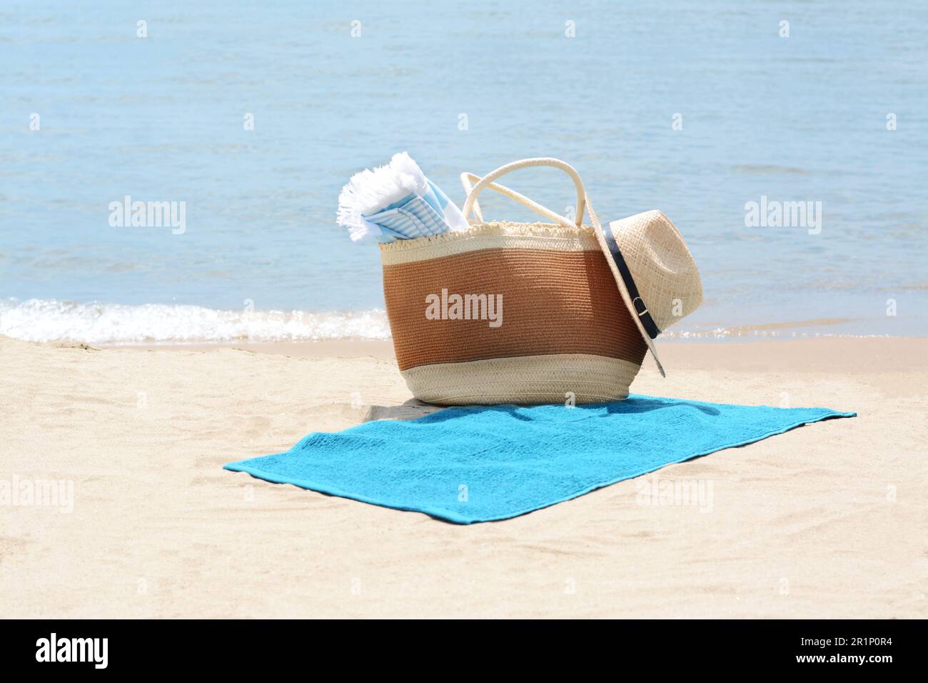 Bag with blanket, beach towel and straw hat on sandy seashore Stock ...