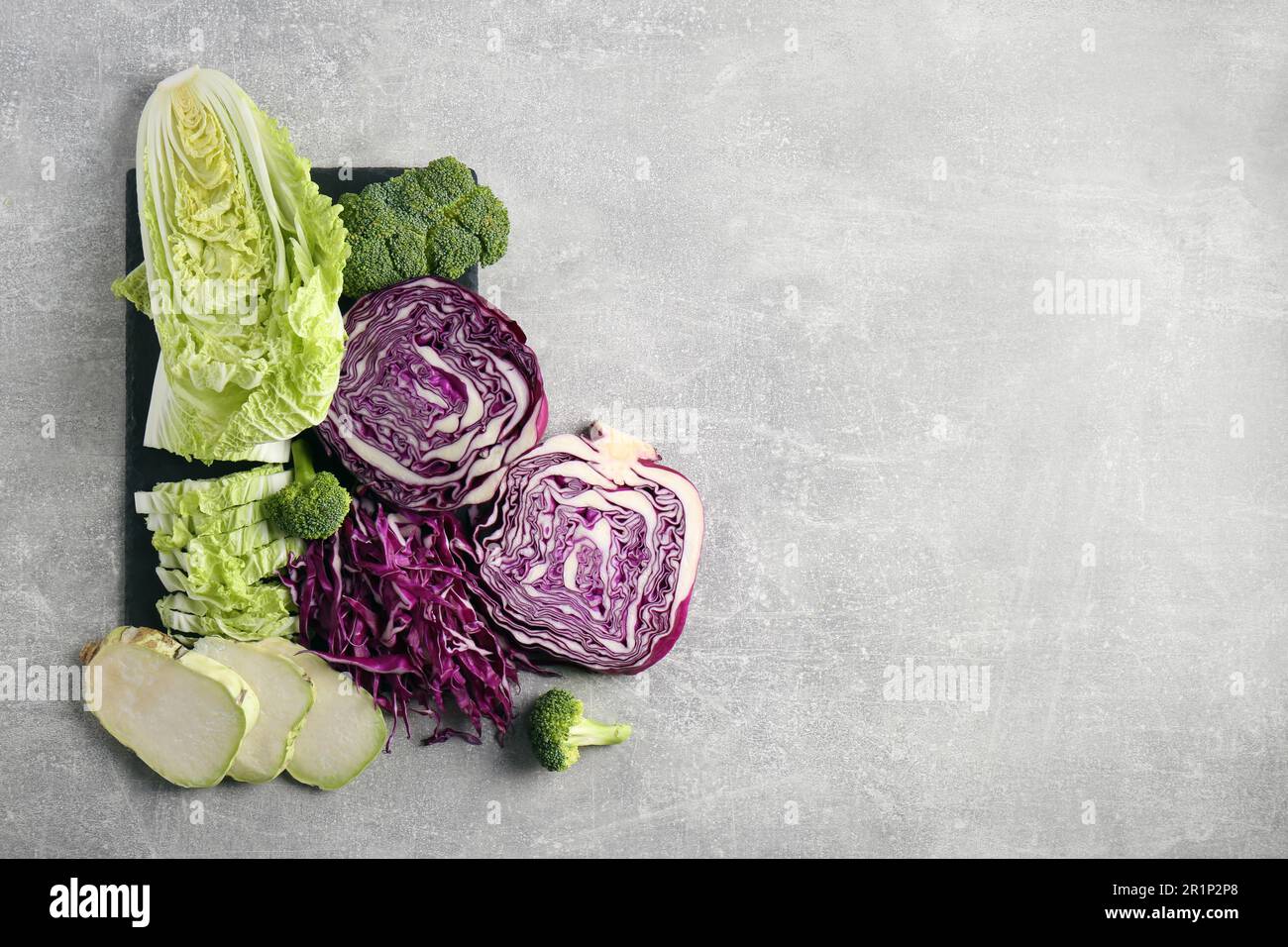 Different types of cut cabbage on light grey table, flat lay. Space for ...