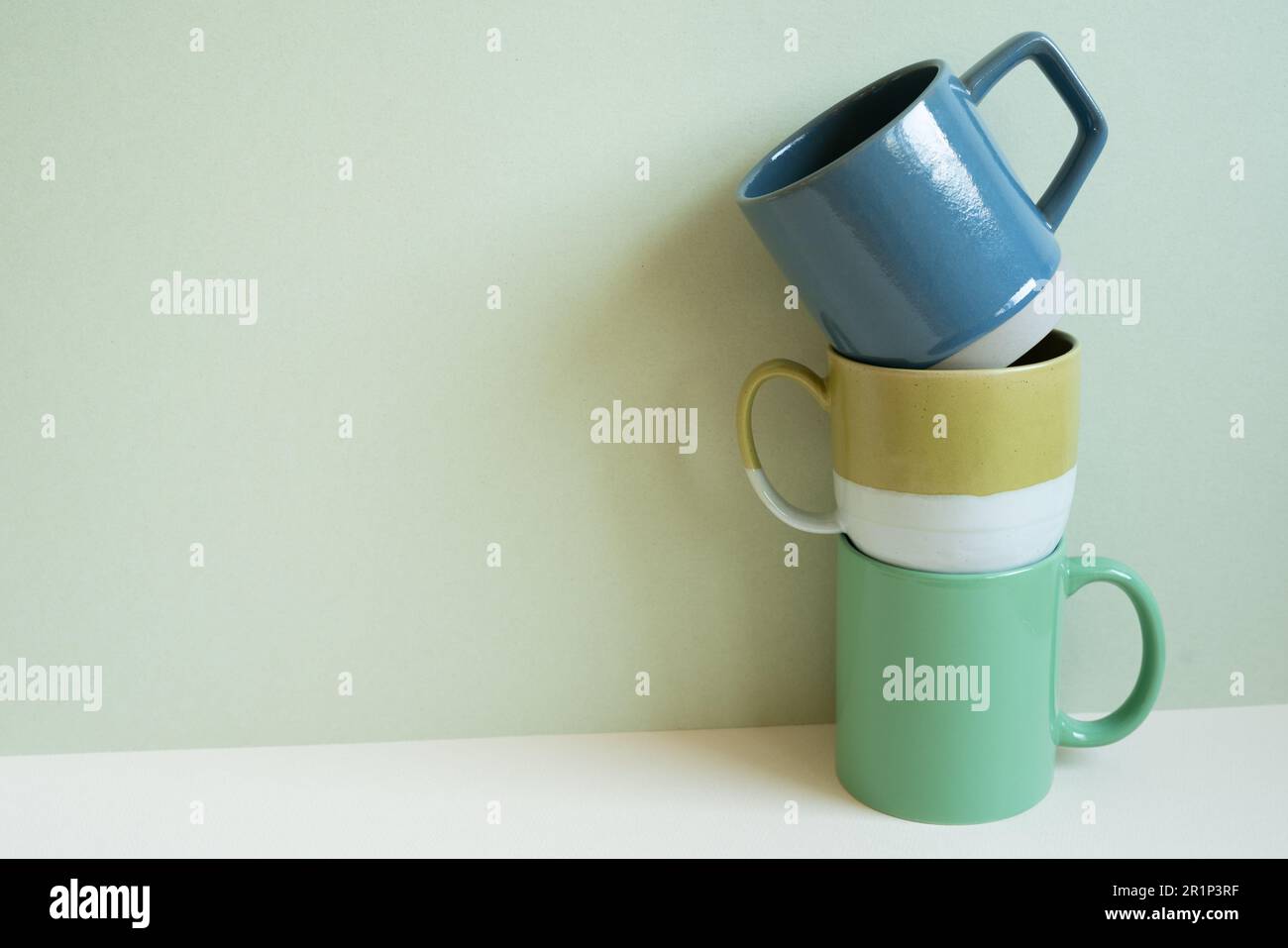 Stack of blue and green mug cups on white table. mint wall background. copy space Stock Photo