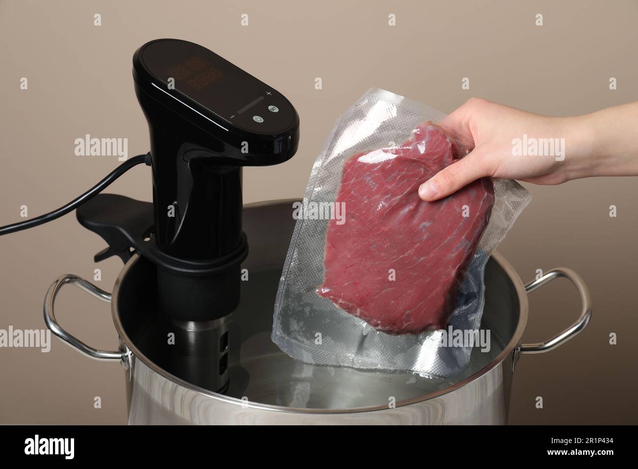 Woman putting vacuum packed meat into pot with thermal immersion