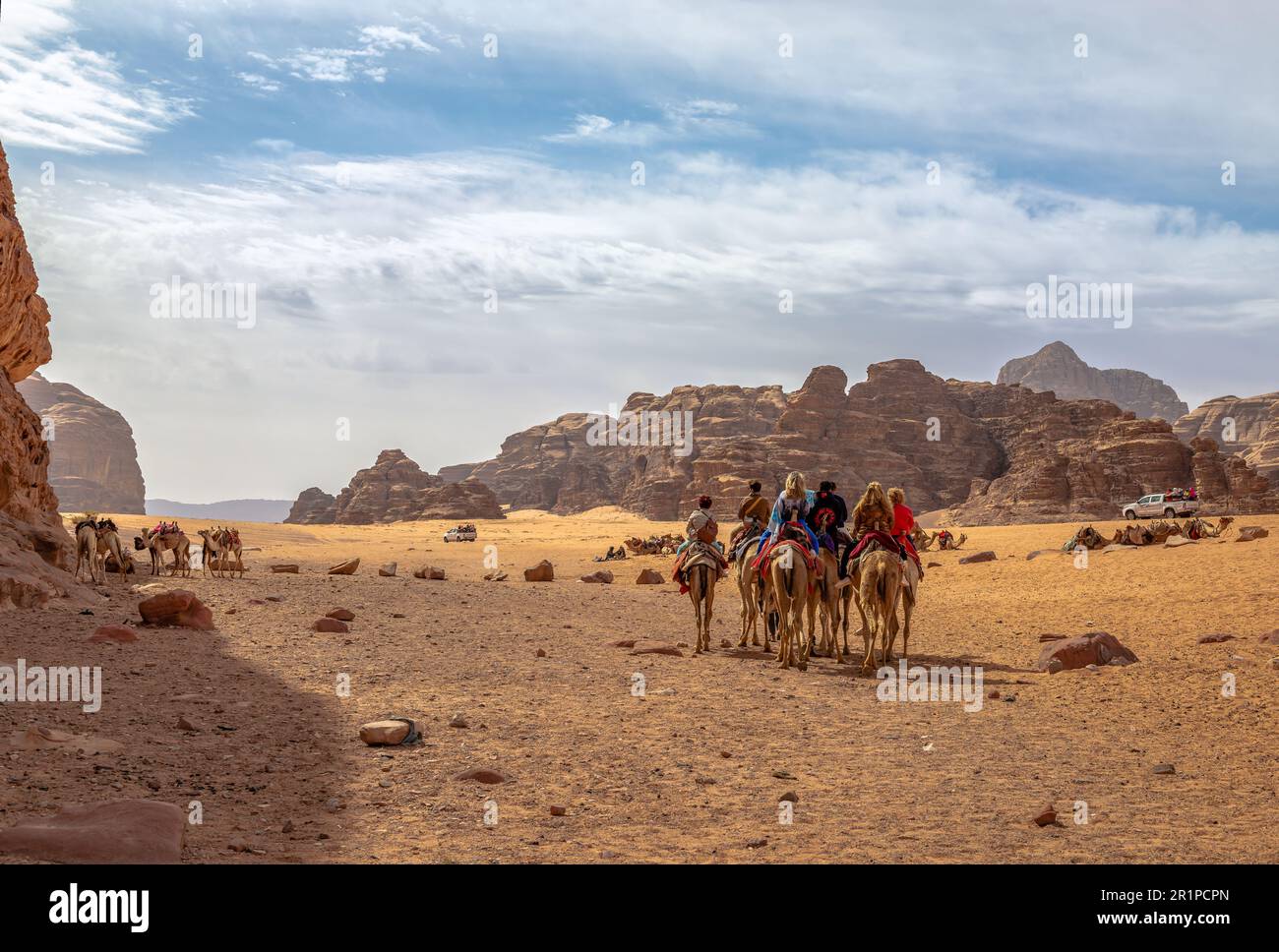 Tourists enjoy a ride with camels in the desert of Wadi Rum, in Jordan. Stock Photo