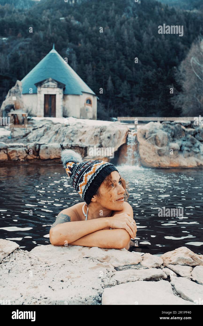 Wellness tourism vacation. Female people enjoying warm thermal natural pool water in winter mountain season outdoor leisure activity alone. Travel adventure lifestyle. Alternative wellbeing care body Stock Photo