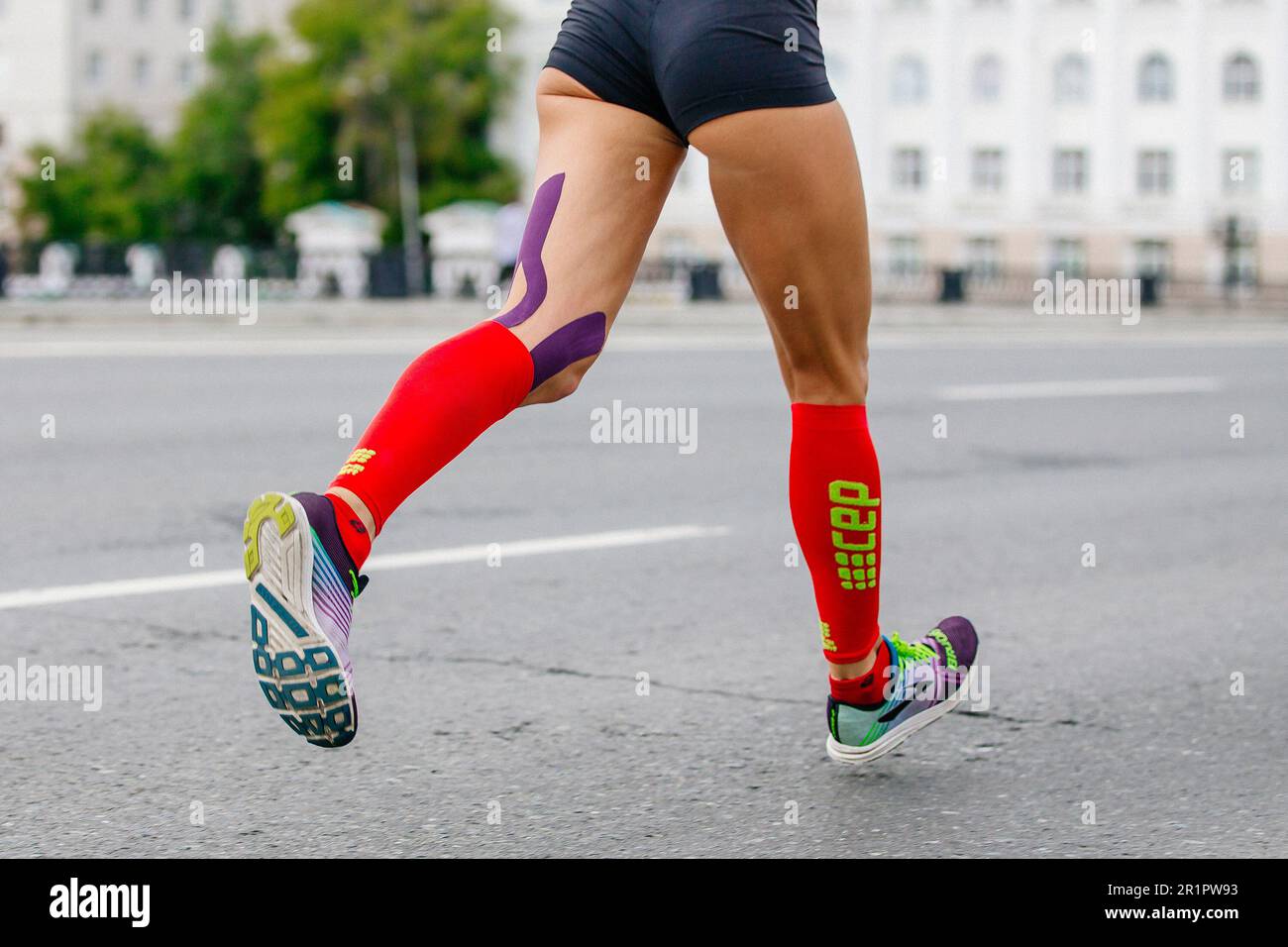 Brooks running shoes and CEP compression socks, legs female runner run marathon in city, summer sports race Stock Photo