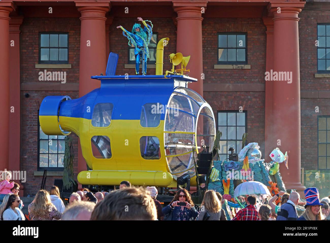 Beatles style yellow and blue , Ukraine flag coloured submarine DJ and dancer, Royal Albert Dock, Pier Head, Liverpool, Merseyside, England, UK,L3 4AF Stock Photo