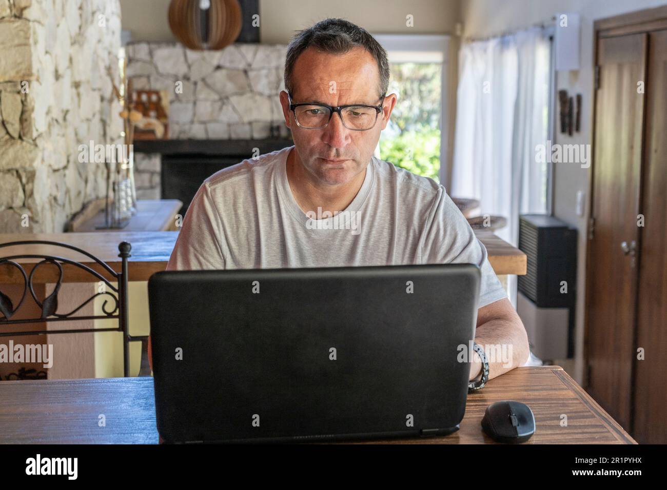 A man working at home, using a laptop computer, using internet, reading news, doing online shopping order for delivery, or studying with device online Stock Photo