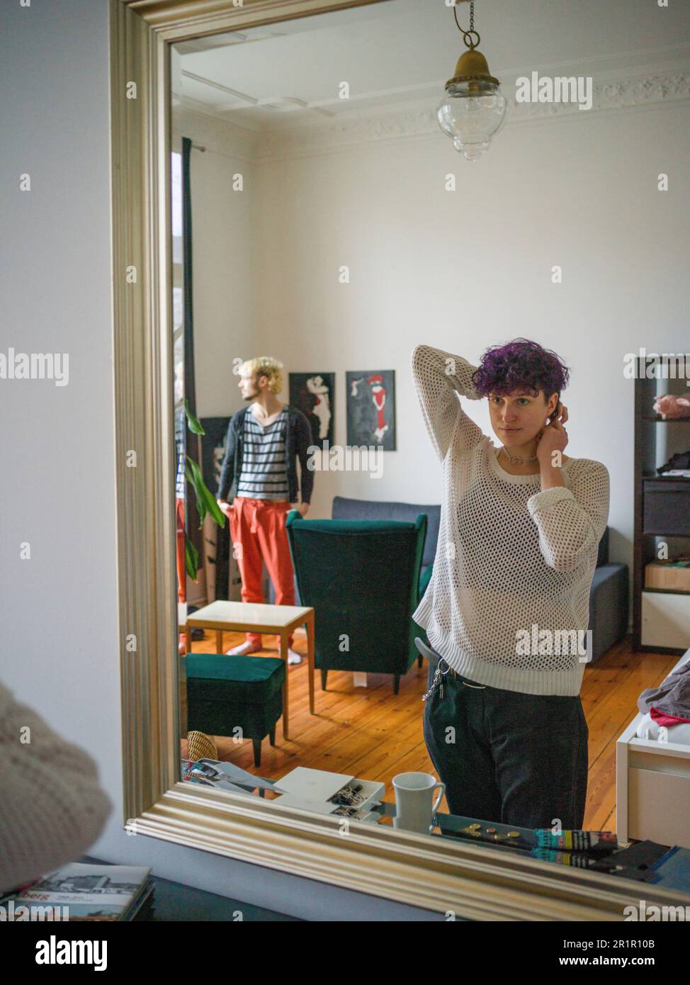 Non-binary person in front of mirror in living room Stock Photo