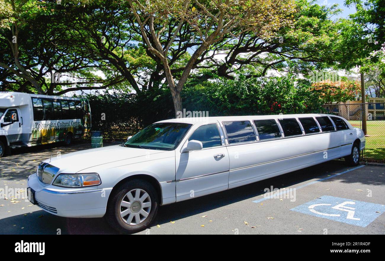A white stretched limo parked at  Moanalua Gardens beside a group of trees, in Honolulu, Hawaii. Stock Photo