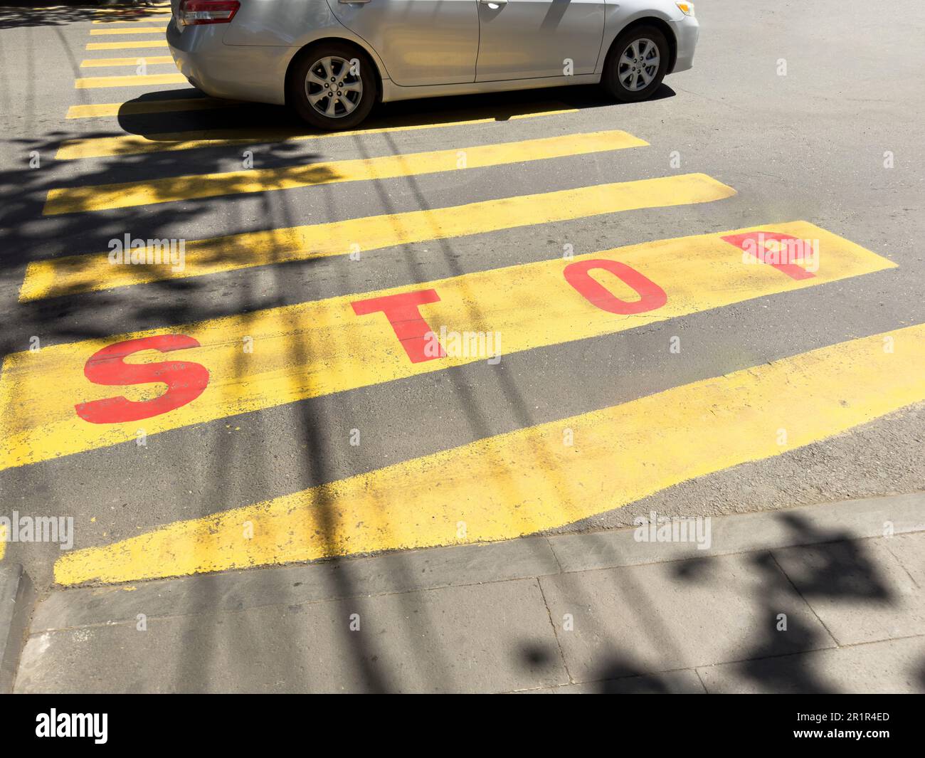 Yellow pedestrian crosswalk across the road with asphalt pavement. Crosswalk road surface marking. Intersection crosswalk. Crosswalk on the street Stock Photo