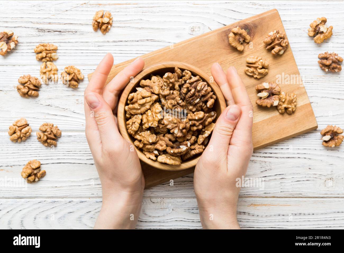 Woman hands holding a wooden bowl with walnut nuts. Healthy food and ...