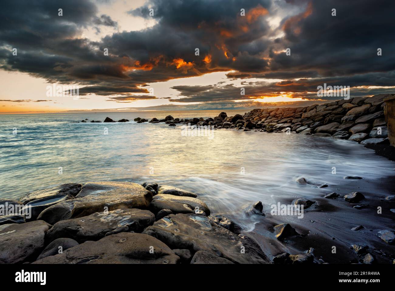 Seascape at sunset over rocks and man-made beach at Calheta, Madeira ...