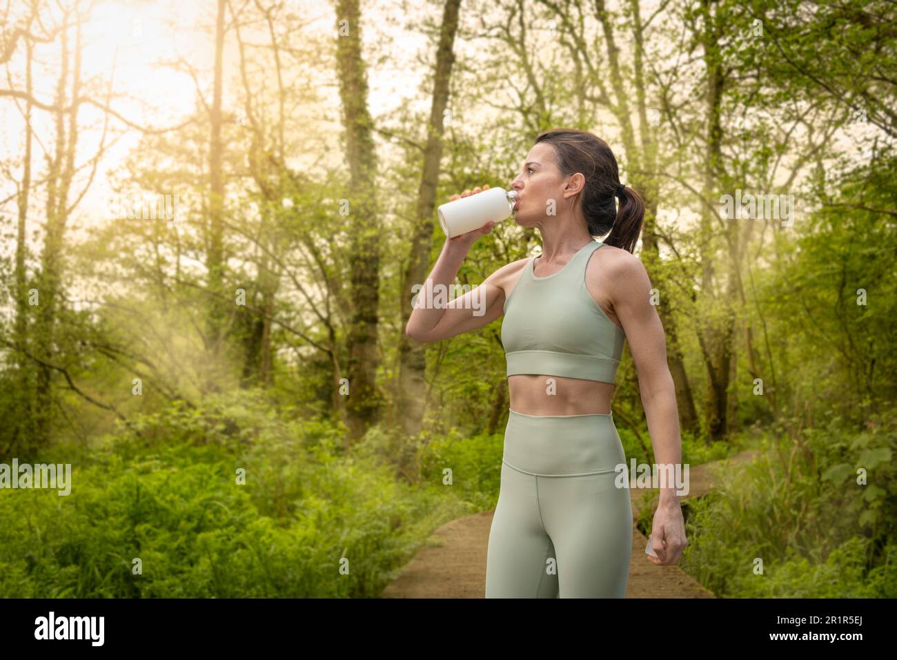 beautiful woman drinking water from a bottle after running workout