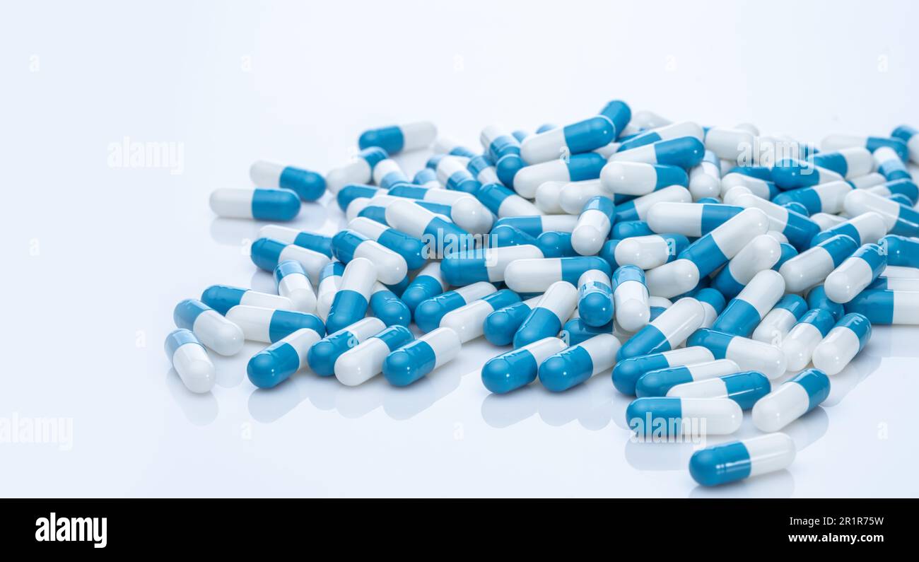 Pile of blue and white capsule pills. Pharmacy product. Prescription drug. Healthcare and medicine. Pharmaceutical industry. Pharmaceutical science. Stock Photo