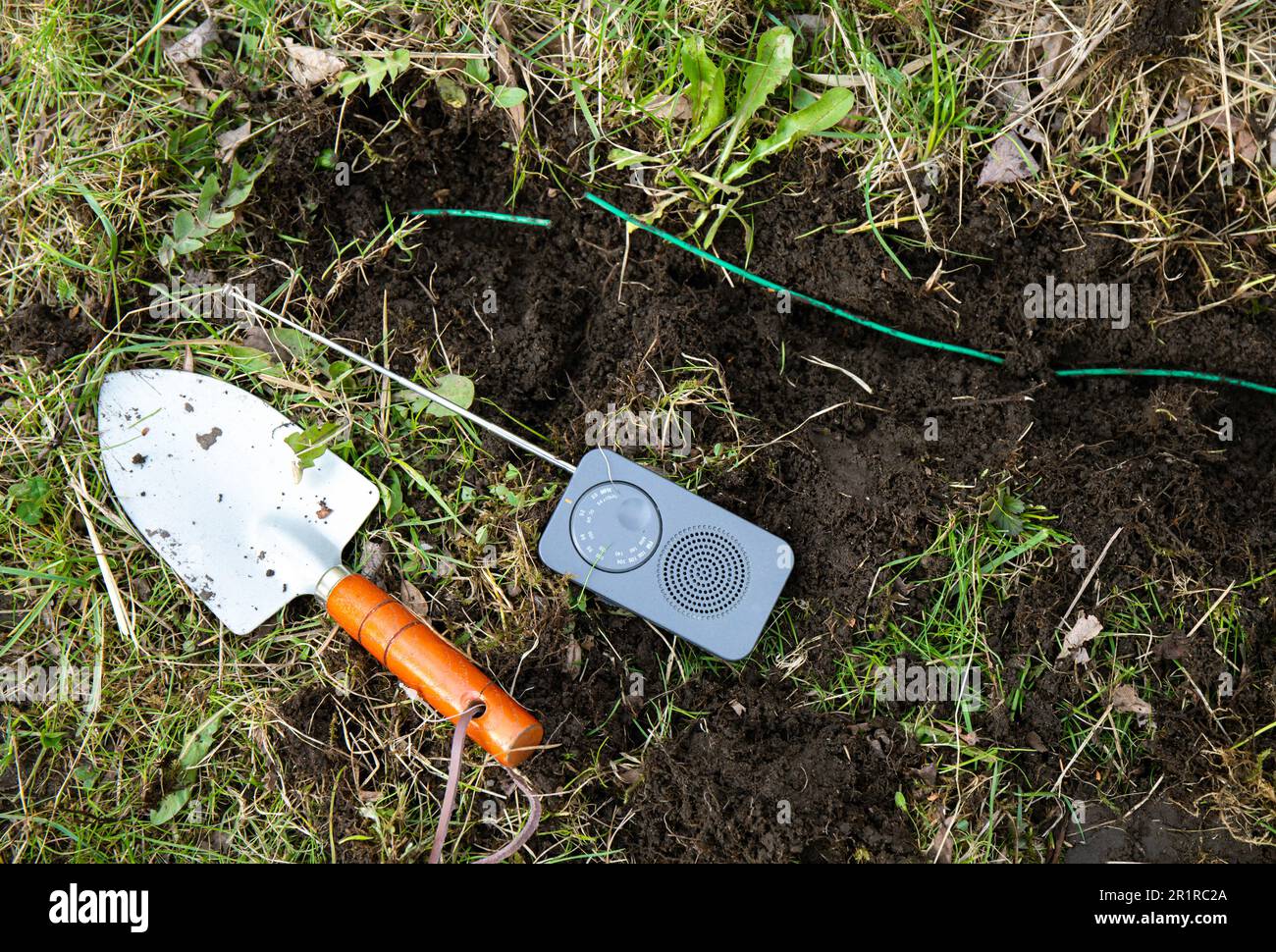 How do you find a break in a robotic mower perimeter wire. Using small hand held battery operated AM radio interference signal to locate broken part . Stock Photo