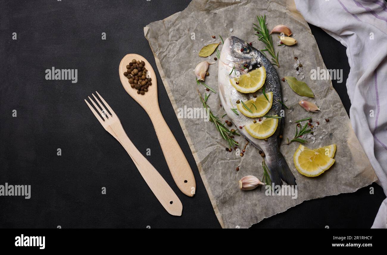 Raw whole dorado fish on brown parchment paper and spices for cooking