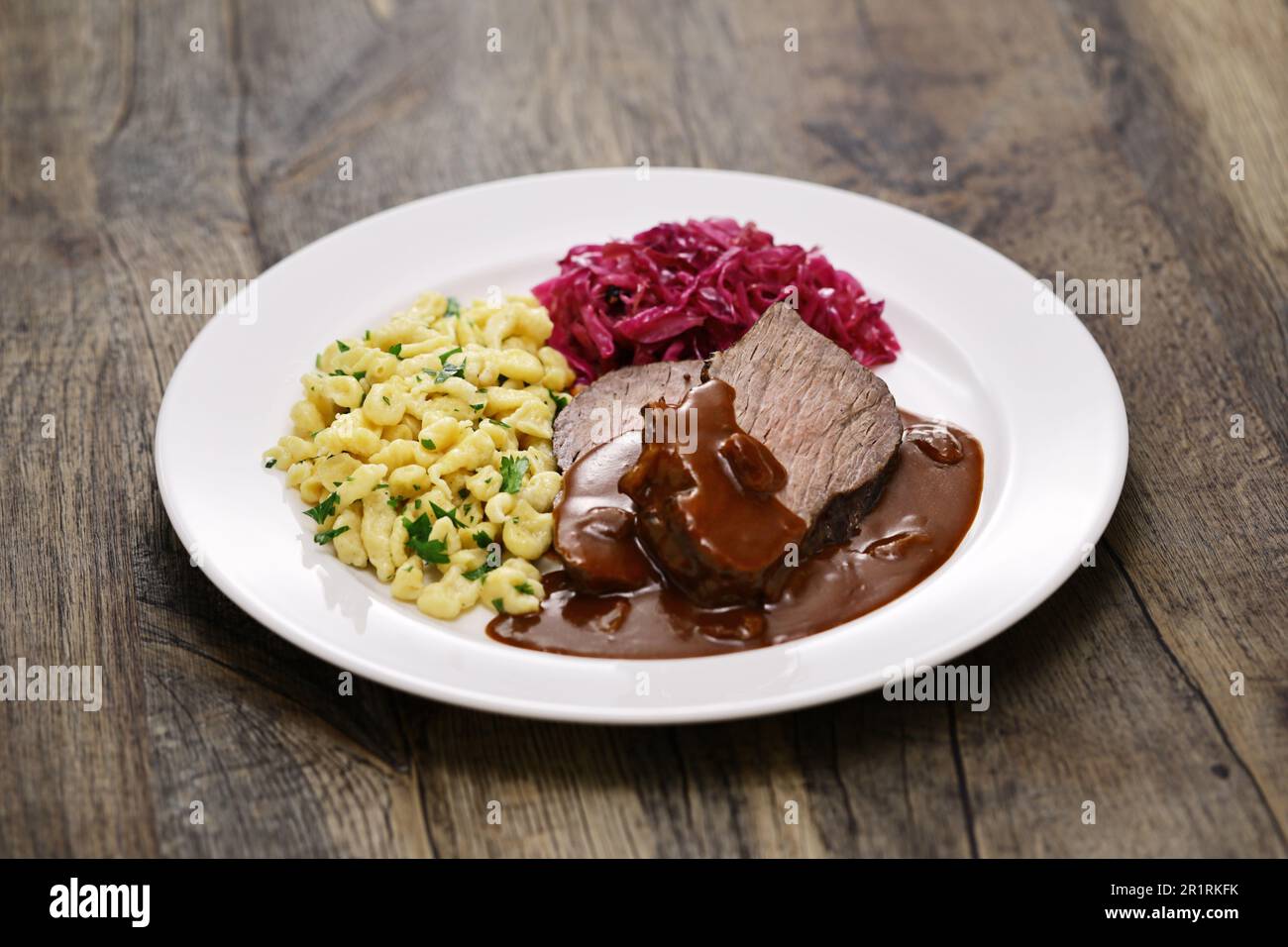 Sauerbraten(tenderized beef marinated in vinegar and vegetables for several days and then braised), Rotkohl(braised red cabbage), Spaetzle (Small past Stock Photo