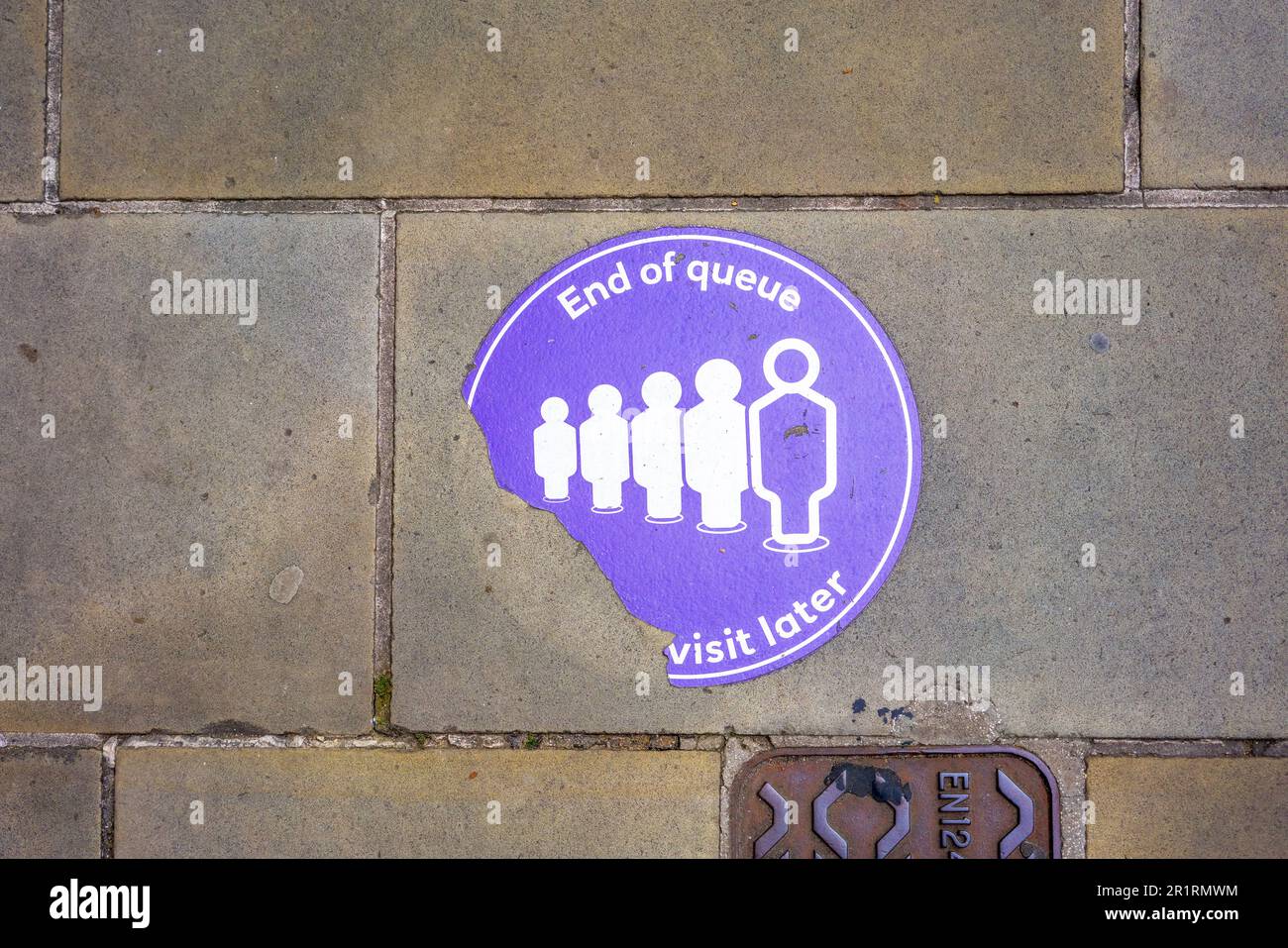 A torn pavement sticker depicting a line of people marking the end of a queue Stock Photo