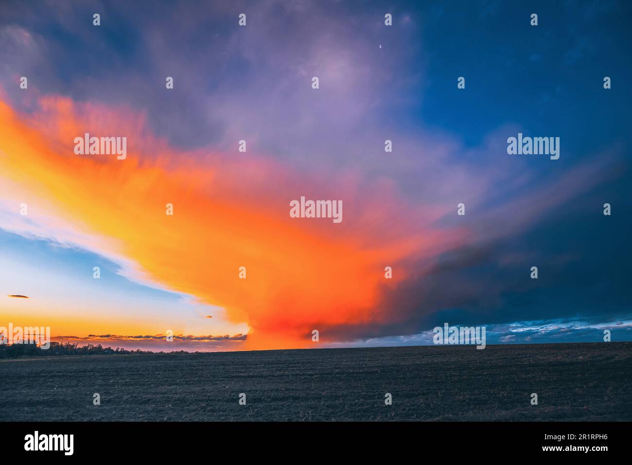 Spring Field At Sunset Sunrise. Morning Sunrise Evening Sunset Sky Above Dark Countryside Meadow Landscape. Spring Nature. Stock Photo